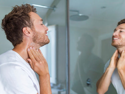 man applying shaving gel in the mirror