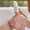 Woman applies white lotion from a white pump bottle onto her tanned leg. Her manicured hands hold the bottle and spread the c