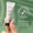 A hand holds a tube of Green People Scent Free Eye Cream 10ml against a green background with a Dermatologically Tested icon.