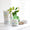 A white jar of Organic Babies Mum & Baby Rescue Balm sits on a bright surface next to a wooden toy mouse and green plant vase.