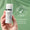 A hand holds a bottle of Age Defy+ Tinted DD Moisturiser SPF 15 against a green background with a dermatologically tested seal.