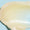A close-up smear of Organic Babies Soothing Baby Salve showing its rich, glossy texture against a light blue background.