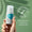 A hand holds a bottle of Oy Deodorant against a soft green background next to a dermatologically tested badge.
